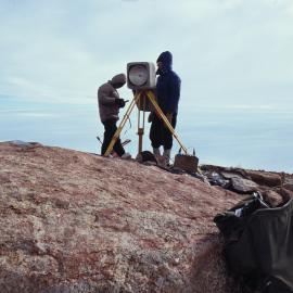 USARP Surveyors carrying out movement survey of Byrd Glacier on Mount Rummage; Byrd Glacier behind