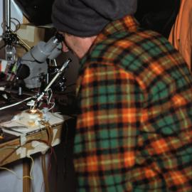 Bill Birch, the Minister of Science and Technology, studying fish moves through a microscope in the Auckland fish hut