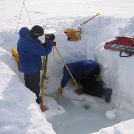 Nic Donnelly (standing) & Aaron Jordan measuring antenna for tide gauge calibration on the sea ice at Scott Base