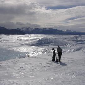 Two people with equipment silhouetted in middle distance