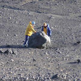 Two people middle distance examining a large rock