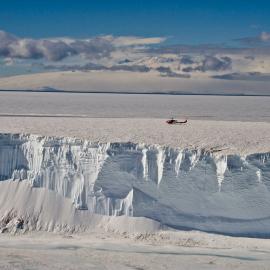 McMurdo Sound. A Bell 212 helicopter hovers over an iceberg
