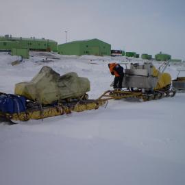 Loading gear on sleds for Granite Harbour camp; Scott Base buildings in the background