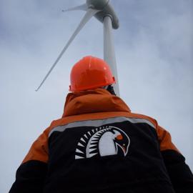 Person in Antarctica NZ clothing looking at a wind turbine