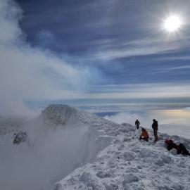 People on a snowy ridge in bright sunshine