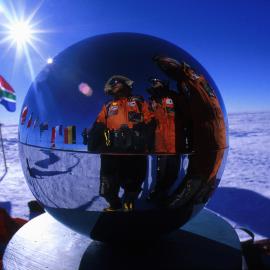 Trio and flags reflected in the South Pole ball