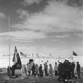 The New Zealand ensign presented by the Bishop of Christchurch to the expedition, is slowly raised at Scott Base