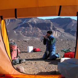 View through tent door of Martin Schiller filming