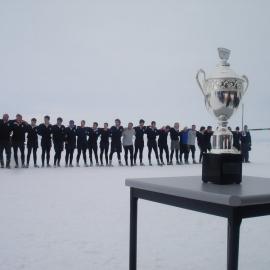 The Antarctic New Zealand rugby team during the national anthem before the annual Rugby match against the Antarctic U.S. rugby team.  The Ross Island trophy can be seen in the foreground