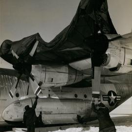 Crew members of C-130 Hercules transport downed in Antarctica's interior with engine trouble cover the plane's engines with a parachute
