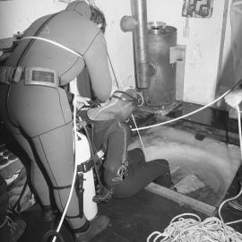 Gary Housley| prepares to dive| assisted by| John Montgomery| Steve Mercer
