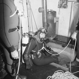 Gary Housley| prepares to dive| assisted by| John Montgomery| Steve Mercer