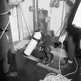 Gary Housley| prepares to dive| assisted by| John Montgomery| Steve Mercer