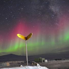 Scott Base sign post with Auroura at night