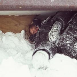 Victoria Metcalf packs snow around the fish hut fishing hole to eliminate draughts