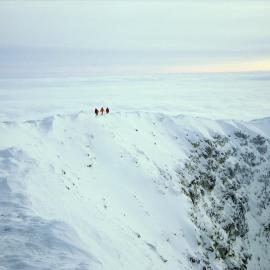 Three figures on snow-covered crater rim