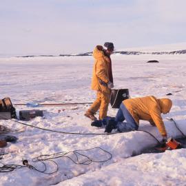 Handing the underwater camera to a diver in a seal hole